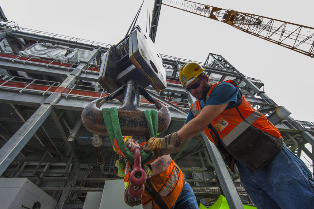 Boilermakers hanging rigging on the crane hook in preparation to install pipe in the unit.