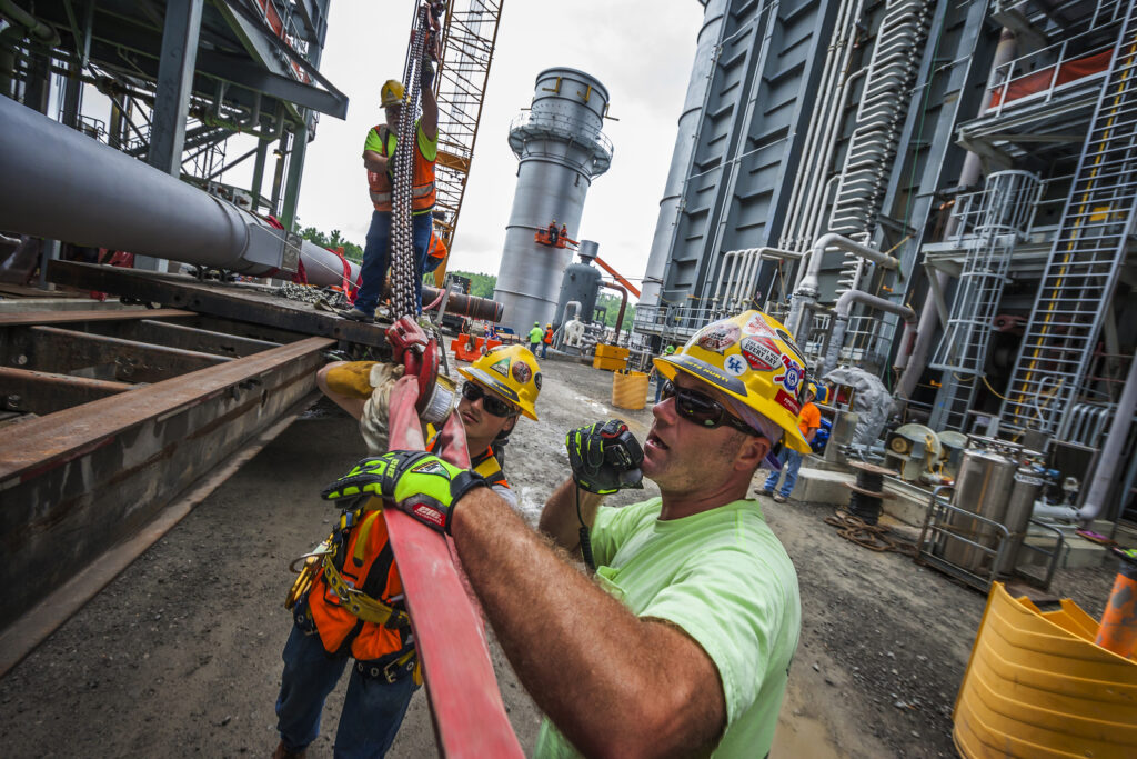 Boilermakers hanging rigging on the crane hook in preparation to install pipe in the unit.