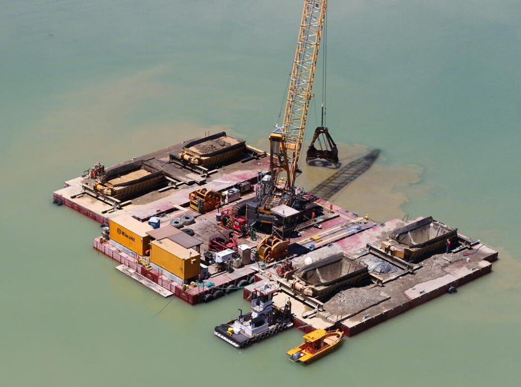 An excavator operates with the unique, hydraulically operated clamshell attachment at the Folsom Auxiliary Spillway project.