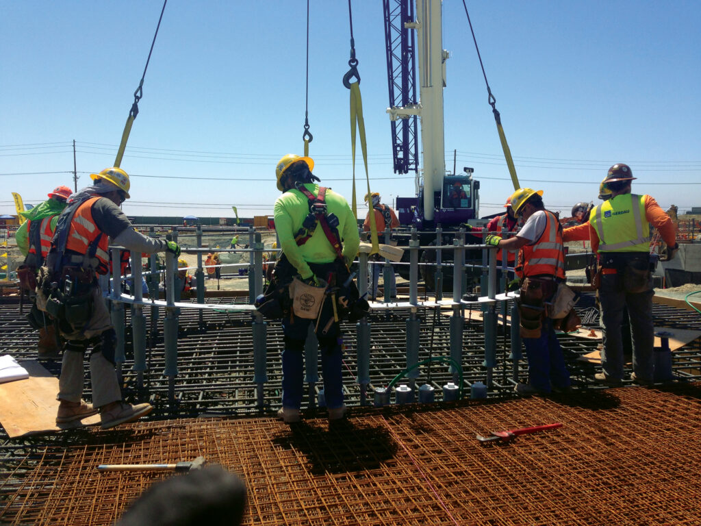 Crews place exhaust stack anchor bolts.