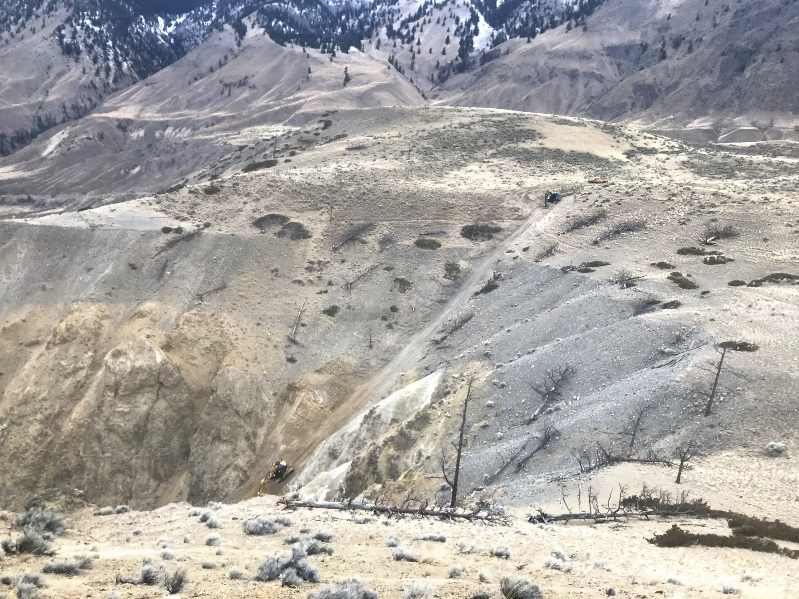 A CAT 325 excavator makes its way down a 70% grade slope tethered to a Falcon winch assist machine. 