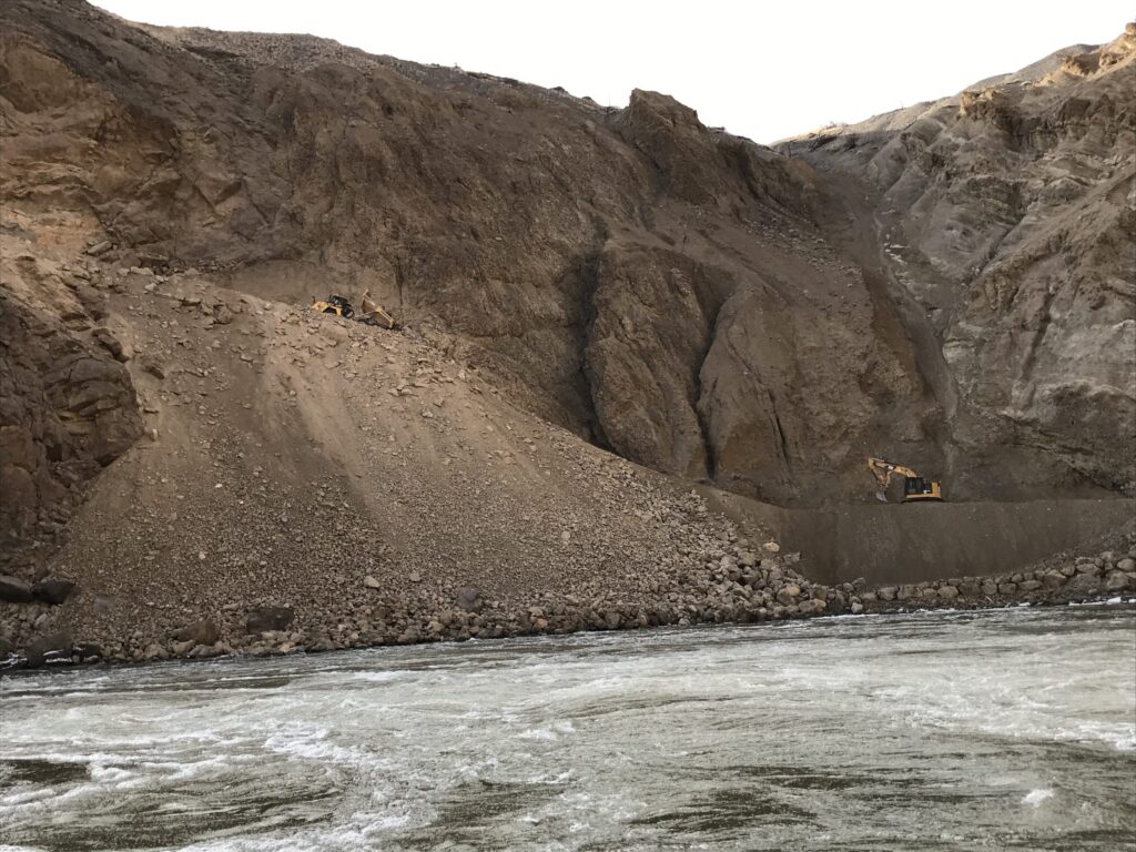 This excavator was used to build the toe of the embankment to minimize material loss in the river as trucks dumped blast rock from the top of the slope.