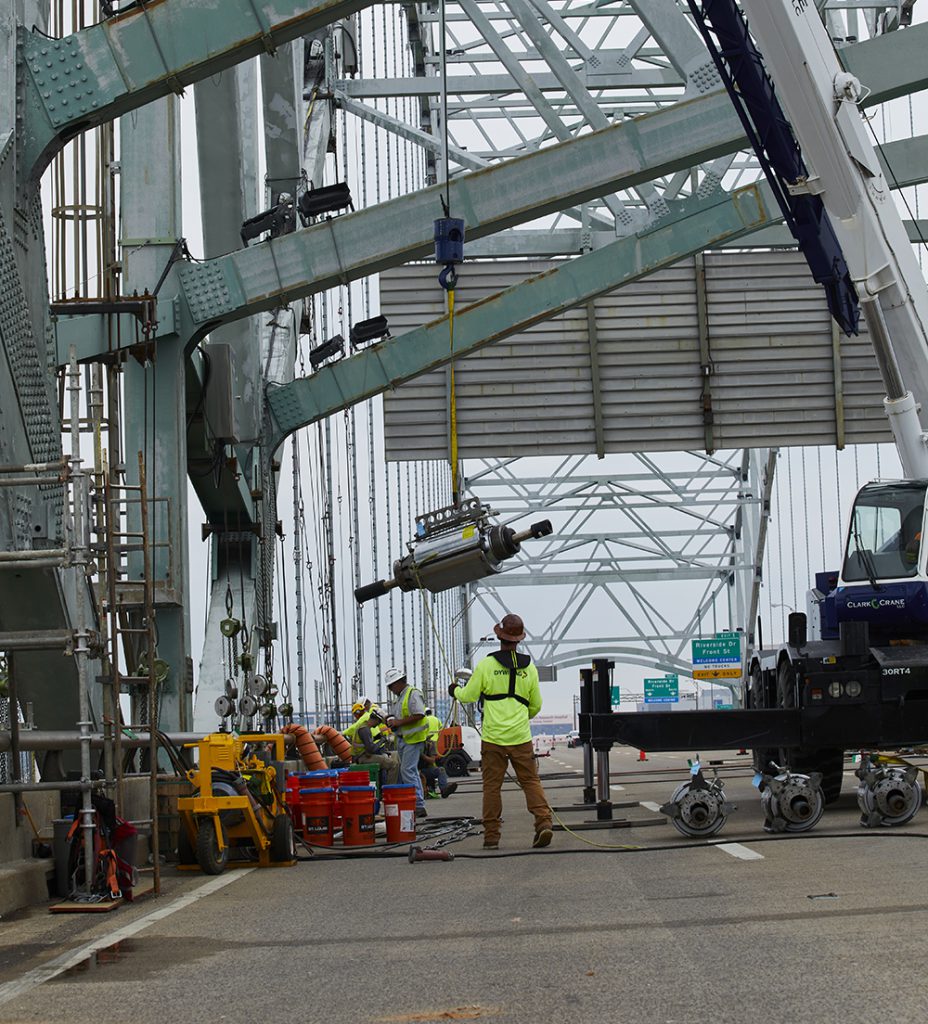 A post-tensioning jack is hoisted into place.