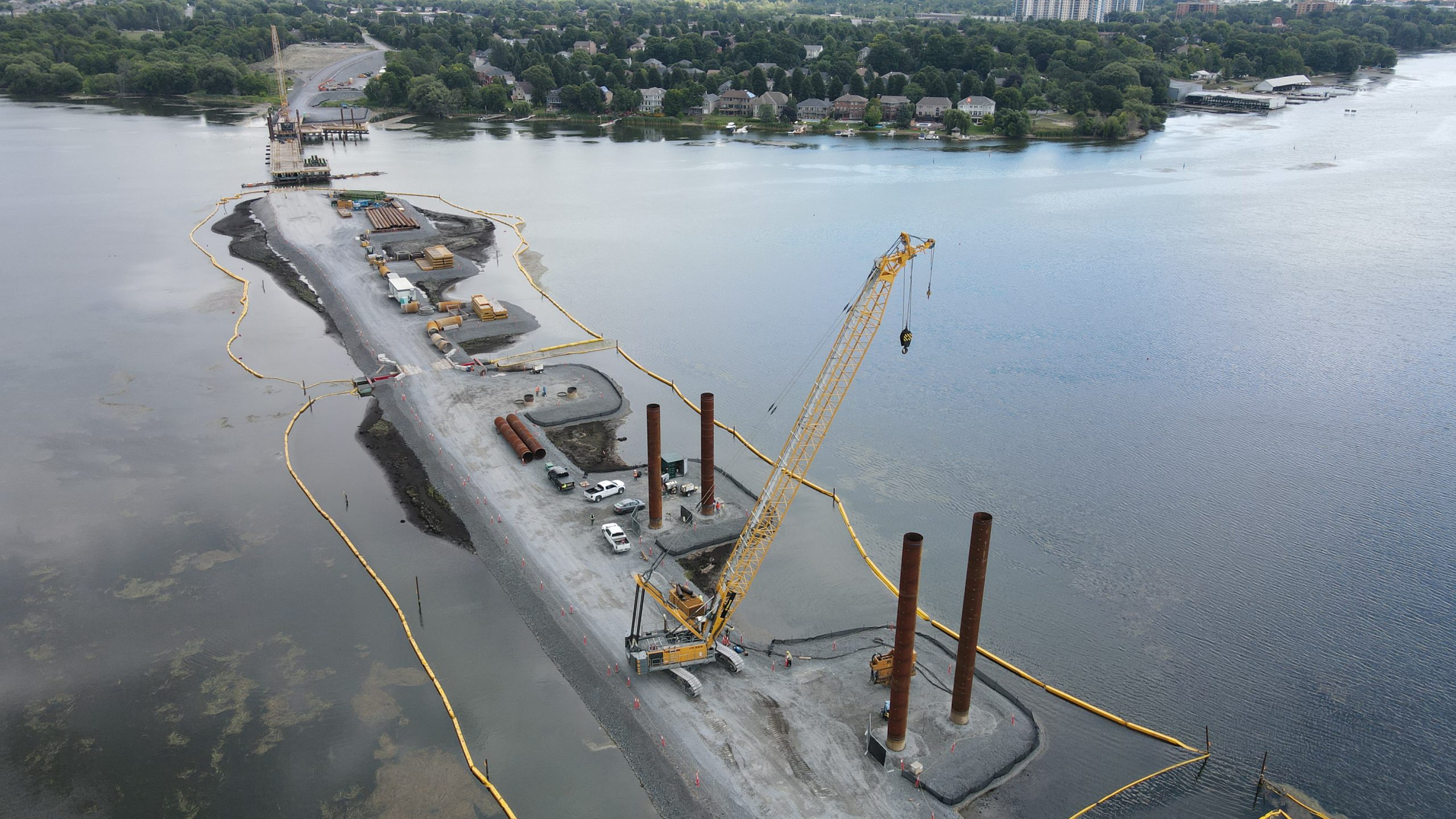 Driving deep foundation casing with one of Kiewit’s HS 895 cranes on the temporary rock causeway. 