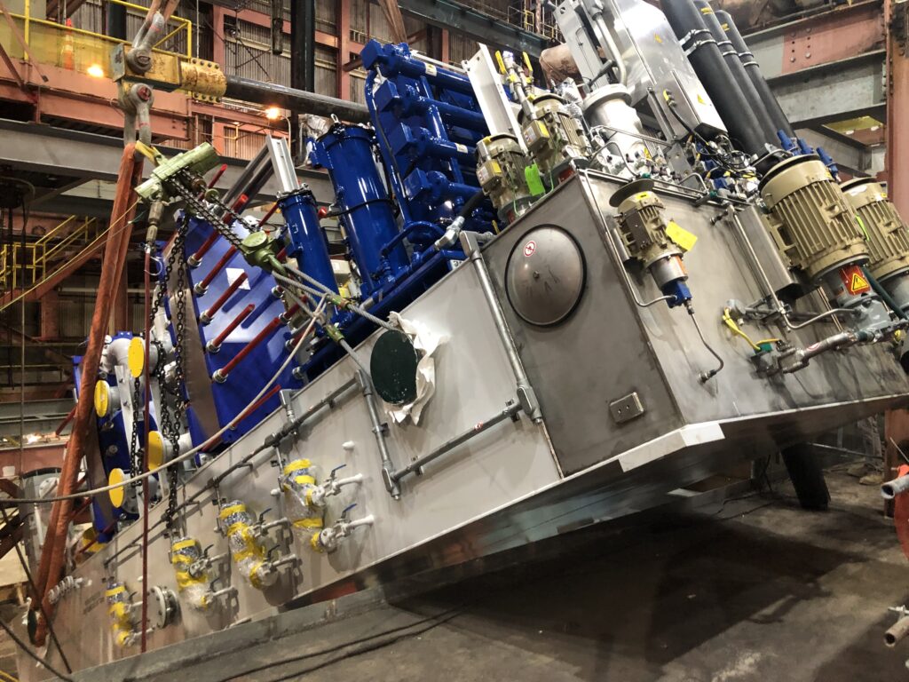 An overhead crane and bull rigging is used to perform a critical lift of the steam turbine lube oil module inside the existing steam turbine.