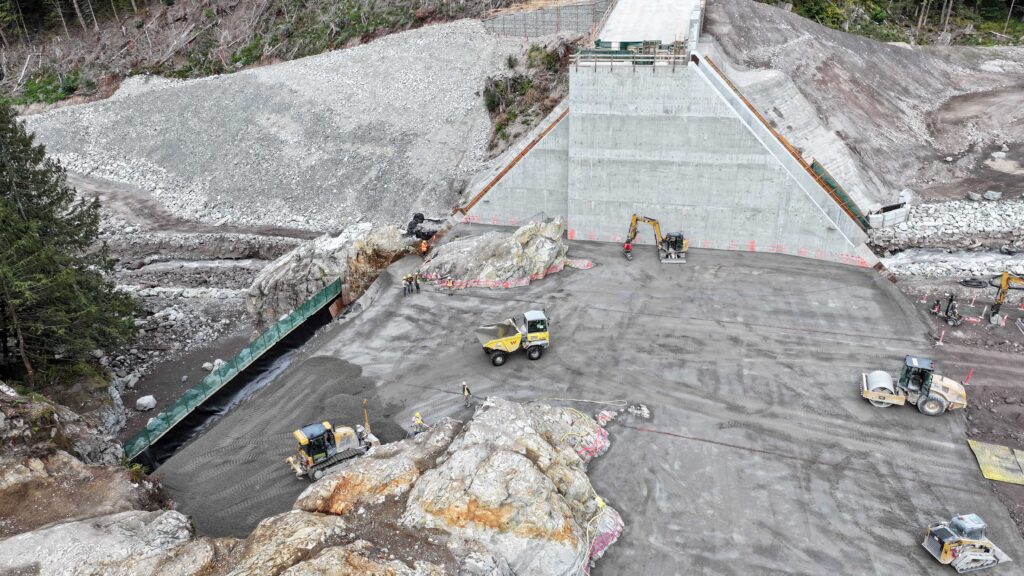 Crew members place roller-compacted concrete for the left abutment of the Cheekeye Debris Flow Barrier.