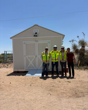 Four Clayco and Kiewit joint venture interns stand in front of a shed during a volunteer project.