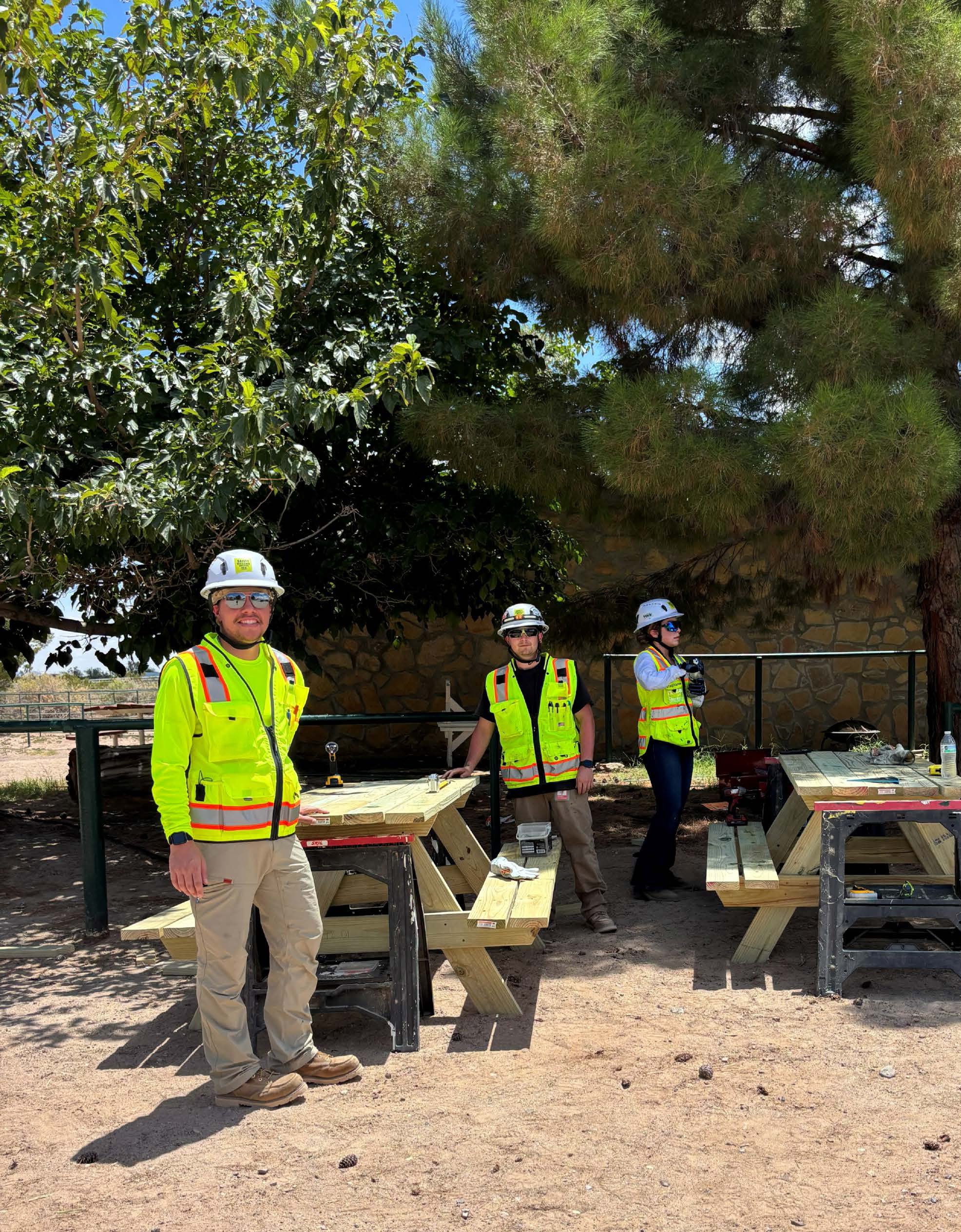 Clayco and Kiewit joint venture interns smile in safety vests and hard hats while working on a volunteer project.