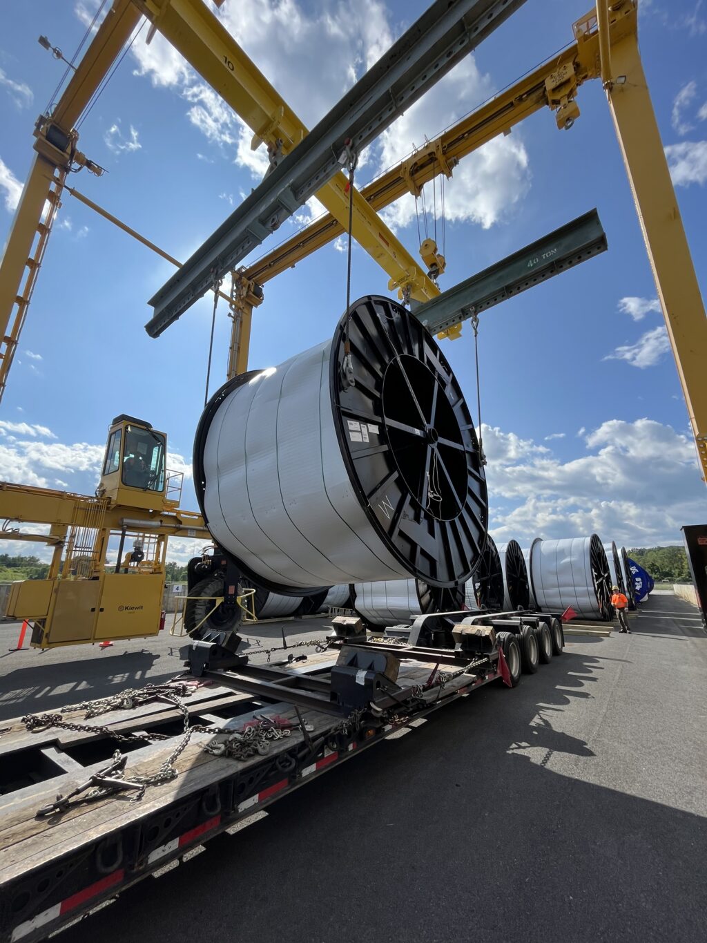 Crews load a cable reel onto a heavy-haul trailer for transport along the Champlain Hudson Power Express transmission line route. 