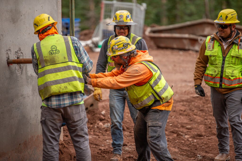 The construction crew installs and secures a structural anchor, working together to keep the project moving forward.